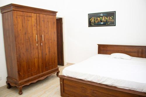 um quarto com uma cama de madeira e um armário de madeira em Mount Guest em Karagampitiya
