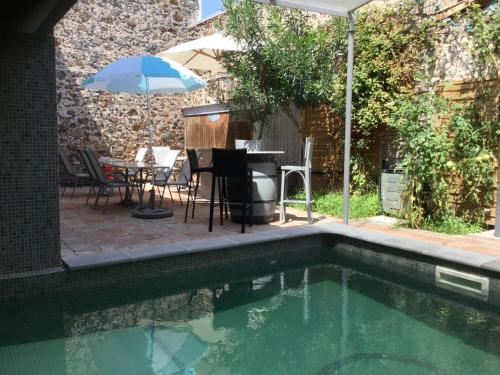 uma piscina com uma mesa e um guarda-sol em Castel&Letti em Agde