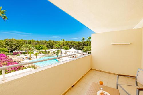 einen Balkon mit Blick auf den Pool und die Palmen in der Unterkunft Hotel Rosella affiliated by Intelier in Sa Coma