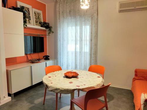 een eetkamer met een tafel en oranje stoelen bij Tre Continenti - Appartamento con parcheggio privato in Ronchi dei Legionari