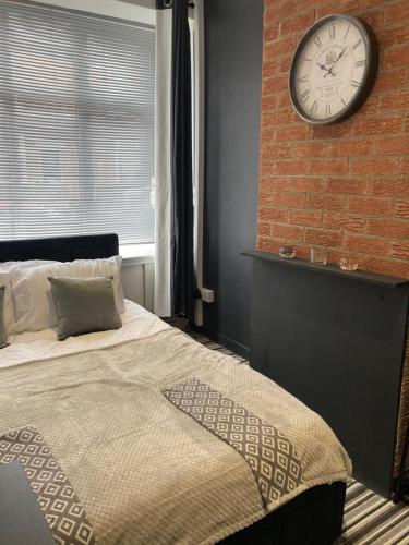 ein Schlafzimmer mit einer Ziegelwand und einer Uhr an der Wand in der Unterkunft Apartment 8 - Luxury Living & free parking in Nottingham