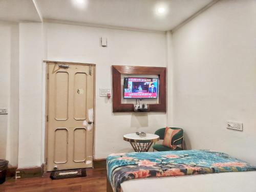 Habitación con cama y TV en la pared. en Hotel Florence, en Siliguri