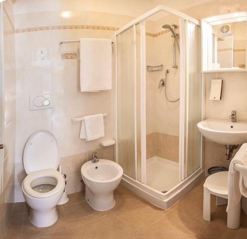 a bathroom with a toilet and a shower and a sink at Hotel Derby S in Lido di Jesolo