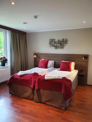 a bedroom with a large bed with red pillows at Gamleby Hotell in Gamleby