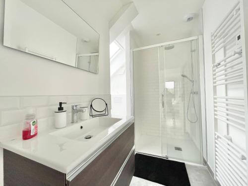 ein weißes Bad mit einem Waschbecken und einer Dusche in der Unterkunft LA CASA SA TRINXA - 300 m des plages - Pointe de Beg-Meil in Fouesnant