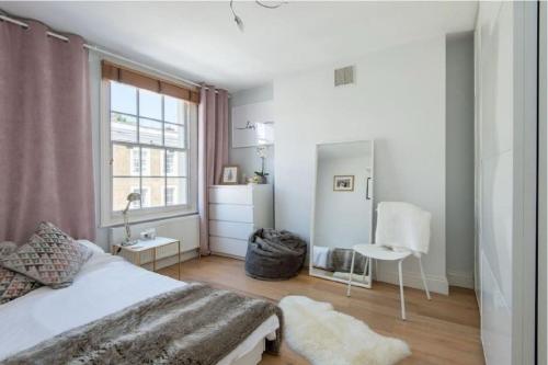 - une chambre avec un lit blanc et une fenêtre dans l'établissement Stylish 2 FLOOR 2BED house 1 MIN walk to Camden station! FREE PARKING!, à Londres