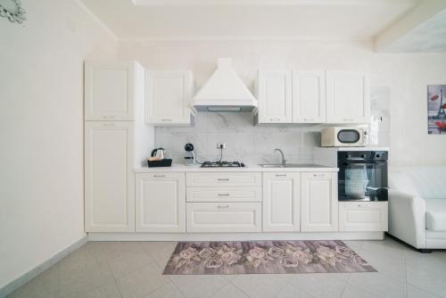 una cocina con armarios blancos y una alfombra en el suelo en La dimora delle zite, en Nápoles