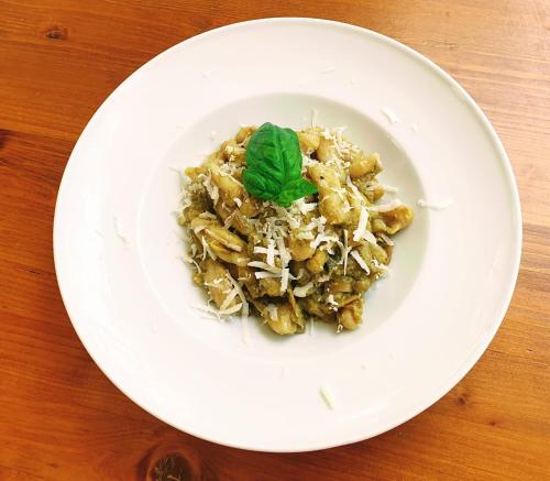 ein weißer Teller mit Pasta und grüner Garnierung in der Unterkunft Green House Oasi Fiume Alento in Prignano Cilento