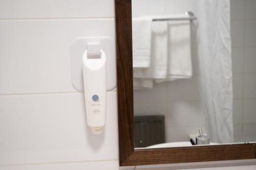 a mirror with a white electric hair dryer on a wall at Cocked Hat by Greene King Inns in Coventry