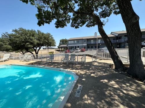 a swimming pool with a tree in front of a building at HillView Inn at Six Flags Fiesta in San Antonio