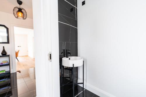 a bathroom with a white sink and black tiles at Escape Ordinary at Lily's Pad in Enniskillen