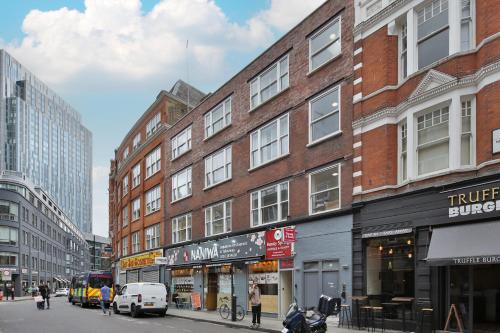 un edificio en una calle de la ciudad con gente y coches en Imperial liverpool street apartments, en Londres