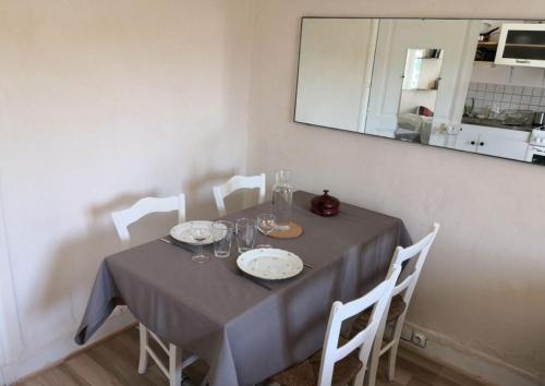 a dining table with a gray table cloth and white chairs at Studio rénové avec goût in Poitiers