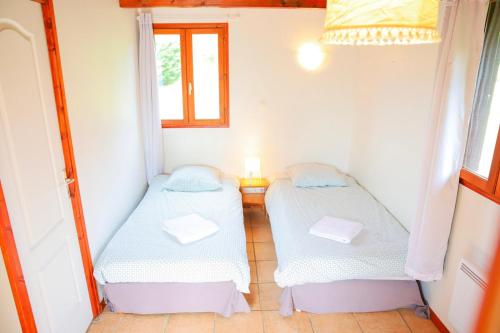 two beds in a small room with a window at Les Cabanes Parisiennes - Chalets 1h30 from Paris - 62P in Sainte-Geneviève-des-Bois