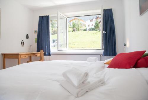ein weißes Bett in einem Schlafzimmer mit einem Fenster in der Unterkunft Central flat for 6 persons Pianura Crapera Lenzerheide in Lenzerheide