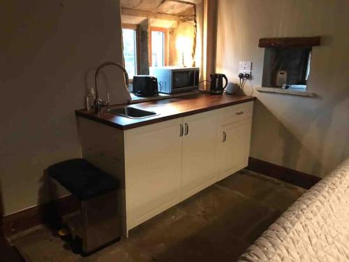 a kitchen with a sink and a counter with a microwave at Knoll Top Cottage in Todmorden