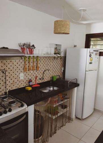 a kitchen with a white refrigerator and a black counter top at Casa com vista mar in Pipa