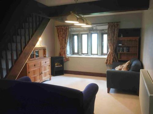 a living room with a couch and a staircase at Knoll Top Cottage in Todmorden