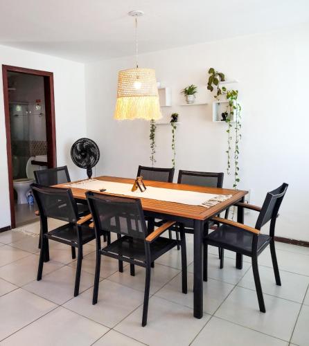 a dining room table with black chairs and a light fixture at Casa com vista mar in Pipa