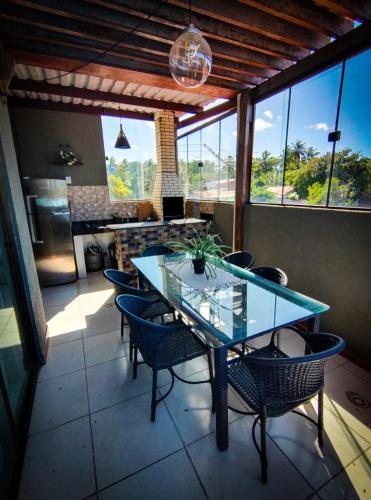 comedor con mesa de cristal y sillas en Casa com vista mar en Pipa