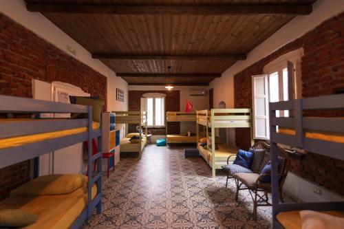 a room with several bunk beds and a room with chairs at Palazzo ReSilente in Castelnuovo Cilento