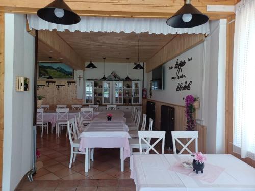 un restaurant avec des tables blanches et des chaises blanches dans l'établissement Penzion Valerija, à Zgornje Jezersko