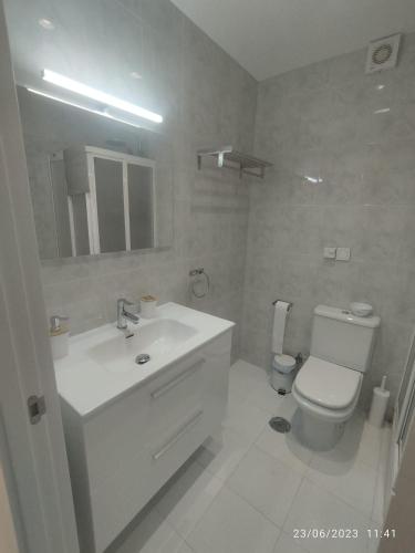 uma casa de banho branca com um lavatório e um WC em Estudio em Torrox Costa