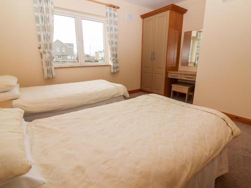 a bedroom with two beds and a sink and a window at 29 Church Field in Doonbeg