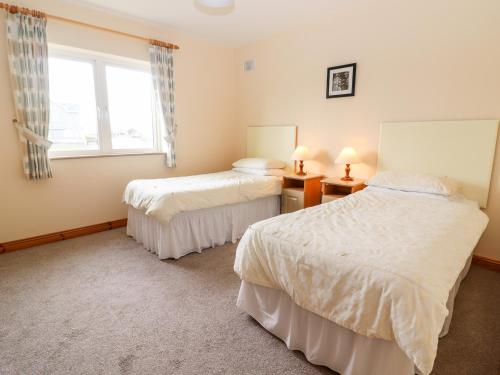 two beds in a room with a window at 29 Church Field in Doonbeg