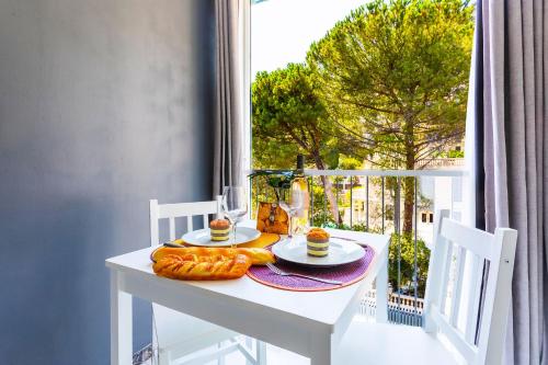 - une table blanche avec de la nourriture sur le balcon dans l'établissement BEAULIEU MARINONI AP4374 By Riviera Holiday Homes, à Beaulieu-sur-Mer