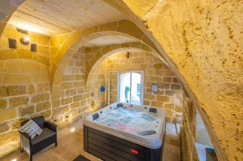 a large bathroom with a tub in a stone wall at Tal-Andar Farmhouse in Kerċem