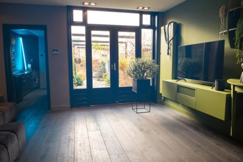 a living room with a door and a window at Bijzonder stadshuis met diepe moderne tuin. in Alphen aan den Rijn