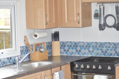 a kitchen with a sink and a stove and cabinets at Lapwing Lodge in Louth