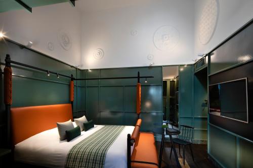 a bedroom with a bed with an orange and green headboard at Hotel Le Colombier in Colmar
