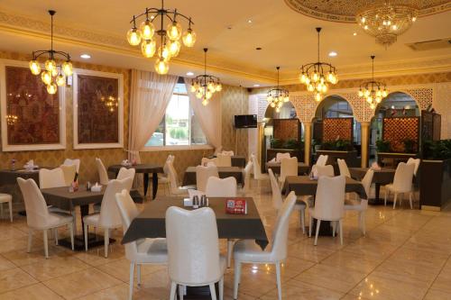 uma sala de jantar com mesas, cadeiras e lustres em Sharjah International Airport Hotel em Sharjah