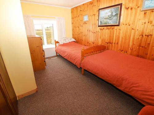 two beds in a room with wooden walls and a window at Forest View 