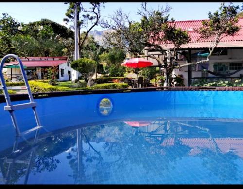 una piscina azul con sombrilla roja en Villa tata Granja autosostenible, en Sasaima