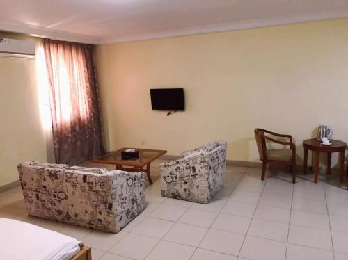 a living room with two chairs and a tv on the wall at Hotel Marjorie `Y` in Tema