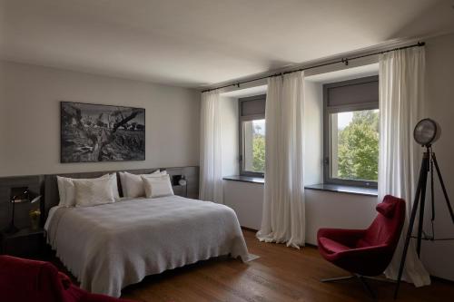 a bedroom with a bed and a red chair and windows at Borgo San Gregorio in Sorbo Serpico