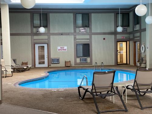 a pool in the courtyard of a hotel with two chairs at Crookston Inn & Convention Center in Crookston