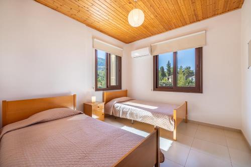 twee bedden in een kamer met twee ramen bij The River House in Trimiklini