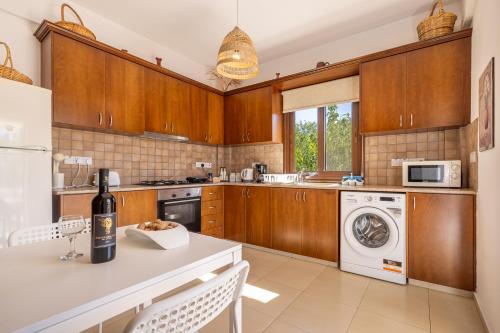 a kitchen with wooden cabinets and a washer and dryer at The River House in Trimiklini