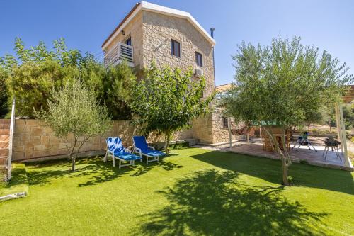 a yard with two chairs and trees and a building at The River House in Trimiklini