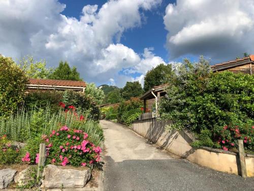 een tuin met bloemen en een weg met huizen bij Résidence Les Chalets de Millau in Millau