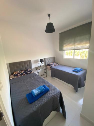 a bedroom with two beds with blue pillows on them at Apartament Villamartin Tosca Golf-Pool in Orihuela Costa