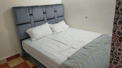 een bed met een blauw hoofdeinde en 2 kussens bij Appartement Relax Marrakech, شقة عائلية بمراكش متوفرة على غرفتين in Marrakesh