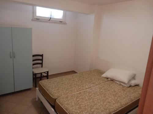 een kleine slaapkamer met een bed en een stoel bij Casa SOAVE in Sperlonga