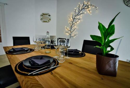 une table en bois avec des assiettes, des verres et une plante dans l'établissement Grand appartement de haut standing en centre-ville, à Montluçon