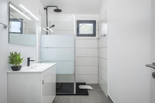 La salle de bains blanche est pourvue d'un lavabo et d'une douche. dans l'établissement Basalt Dwelling I by Madeira Sun Travel, à São Vicente