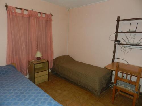 een slaapkamer met 2 bedden en een bureau en een bed bij Lo de Lili in Puerto Madryn